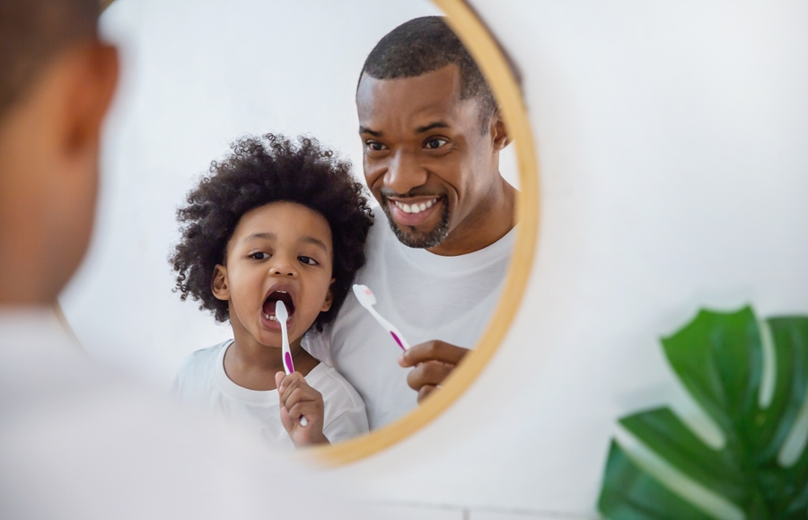 Pappa och son borstar tänderna i badrummet