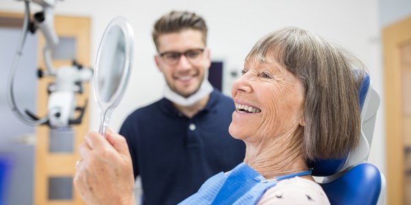 Senior hos tandläkaren tittar sig nöjt i spegeln